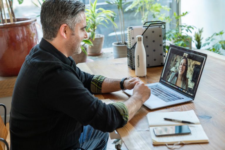 A cozy and organised home office setup with a laptop, notebook, and a bottle of water - a typical virtual assistant's workspace.